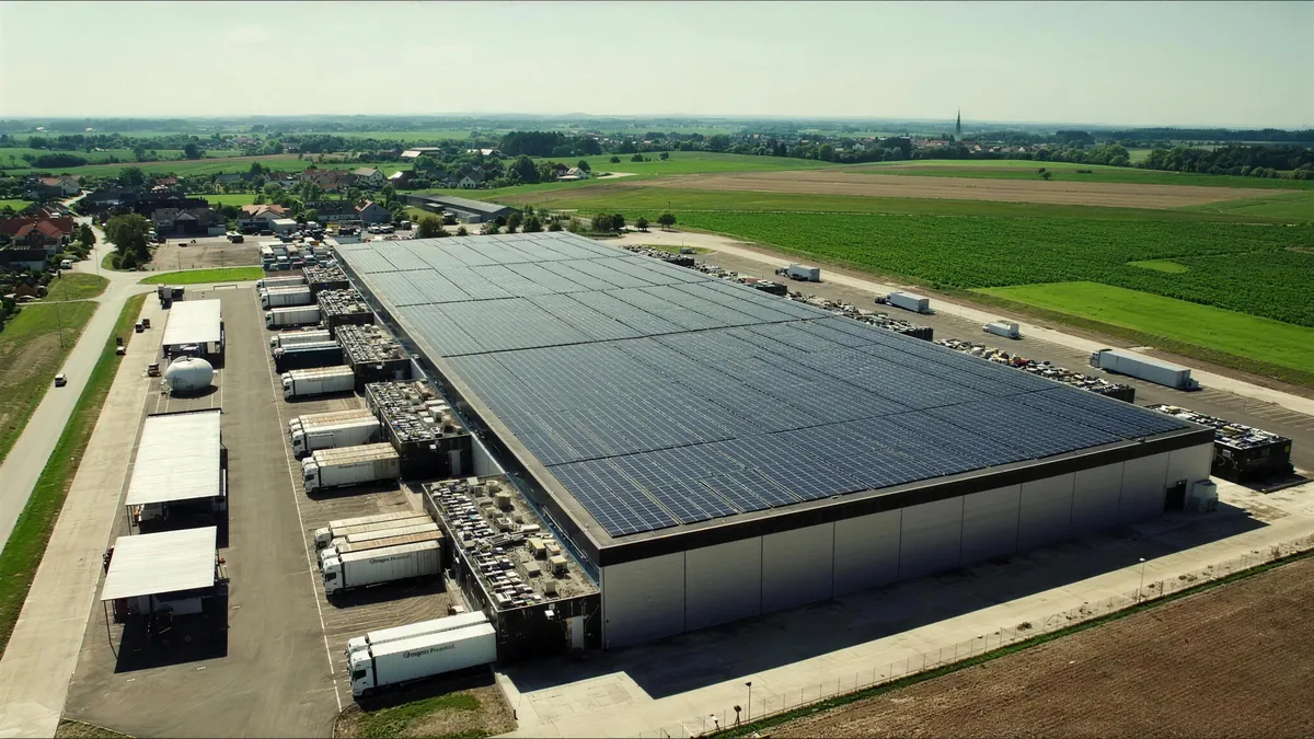 Luftaufnahme eines Logistikstandorts mit Solardach und Lkw an den Laderampen